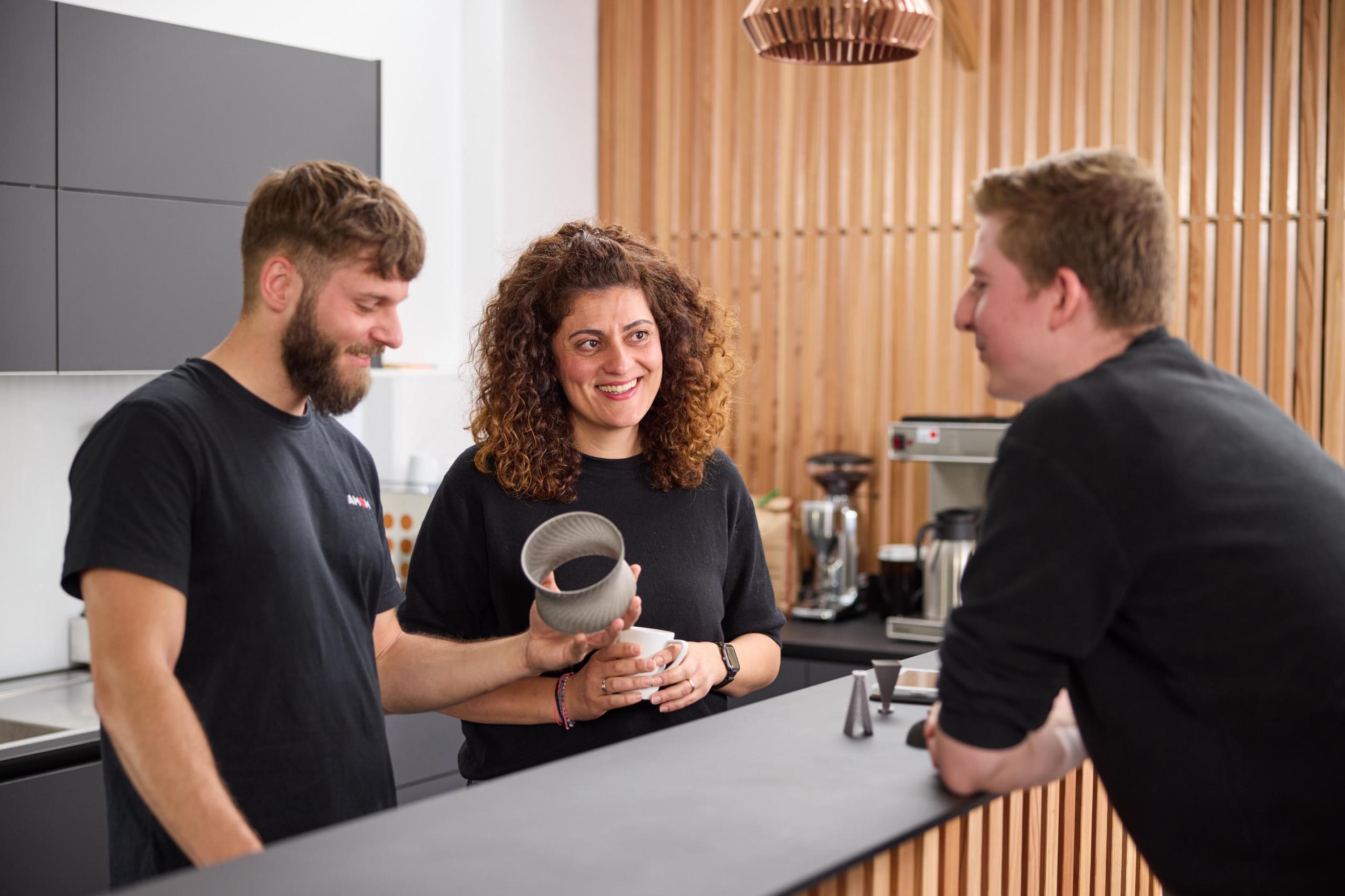 Three Employees at the counter talking about 3D printed parts standing